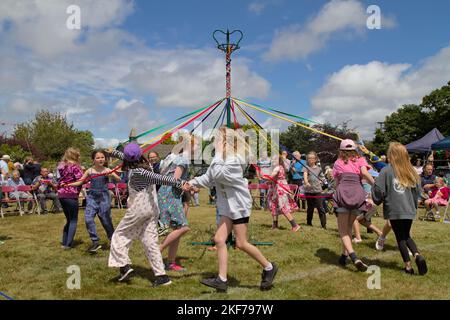 Kinder, die Ribbons halten, tanzen um Einen Maibaum an Einem Summers Day auf der Boldre Village Fair, Großbritannien Stockfoto