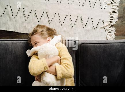 Weiße glückliche Mädchen macht Spaß mit Spielzeug, während auf der Couch zu Hause liegen Stockfoto