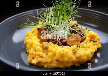 Risotto mit Pilzen, Kürbis und Kräutern auf dunklem Grund Stockfoto