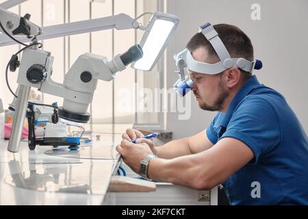 Der Zahntechniker beschäftigt sich mit der Modellierung von künstlichem Zahnersatz. Qualitätskontrolle des Zahnhalses Stockfoto