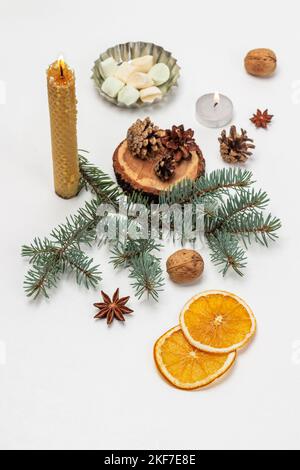 Zapfen auf einem Stumpf, Fichtenzweige und brennende Kerzen. Scheiben von trockenen Orangen. Draufsicht. Weißer Hintergrund. Stockfoto