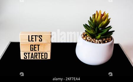 LET'S GET STARTED Text auf Holzblock mit Kaktusblüte, weißem und schwarzem Hintergrund Stockfoto