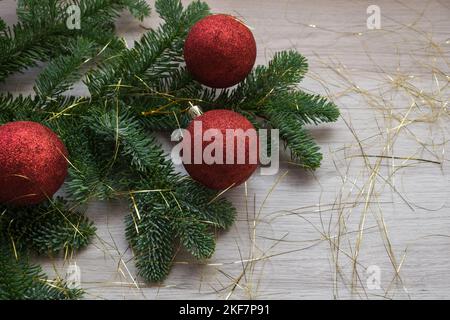 Weihnachtsdekoration. Fir Tree Branch und drei rote Weihnachtskugeln Stockfoto