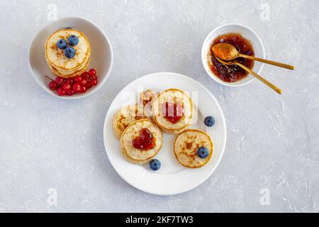 Mini-Pfannkuchen mit herzförmiger Marmelade und frischen Beeren dekoriert, Valentinstag Frühstück Idee, Blick von oben Stockfoto