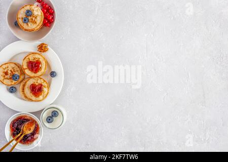 Joghurt und Mini-Pfannkuchen mit herzförmiger Marmelade und frischen Beeren, Frühstücksidee am Valentinstag, Draufsicht, Kopierbereich Stockfoto