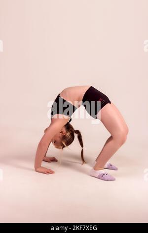 Eine Turnerin macht eine Brücke auf weißem Hintergrund. Junger Athlet Stockfoto