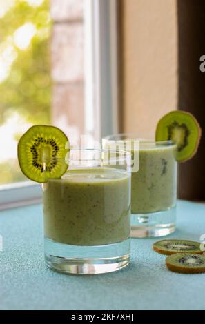 Kiwi-Smoothie in einem Glas auf blauem Hintergrund, unscharfer Hintergrund Stockfoto