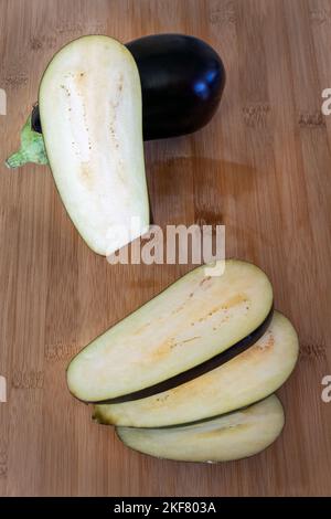 Solanum melongena oder Auberginen- und Auberginenscheiben auf einem Holztisch Stockfoto
