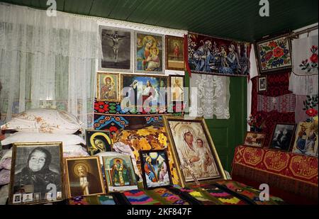 Ilfov County, Rumänien, ca. 2000. Inneneinrichtung eines alten traditionellen Hauses mit einfachen Möbeln, handgefertigten Teppichen und einer Sammlung christlich-orthodoxer Ikonen. Stockfoto