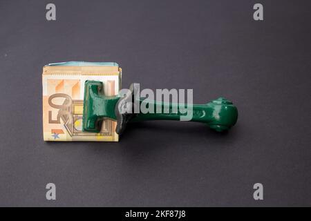 Bild eines Schreinerers und eines Schmieds auf schwarzem Hintergrund mit Euro-Banknoten. Geld wurde eingesperrt und sicher aufbewahrt Stockfoto