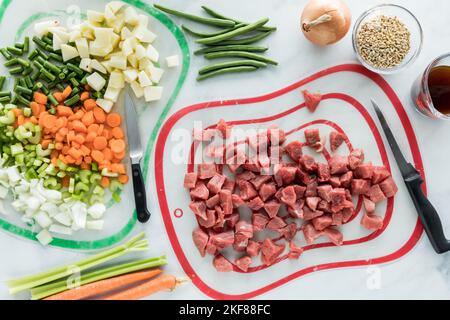 Frisch gehacktes Gemüse und Rindfleisch als Vorbereitung für den Eintopf von Rind und Gerste. Stockfoto