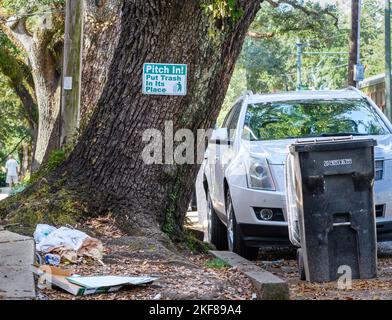 NEW ORLEANS, LA, USA - 9. NOVEMBER 2022: 'Pitch in! Setzen Sie den Müll an seinen Platz, Abfall entlang des Bürgerwegs und Müllwagen auf der Straße Stockfoto
