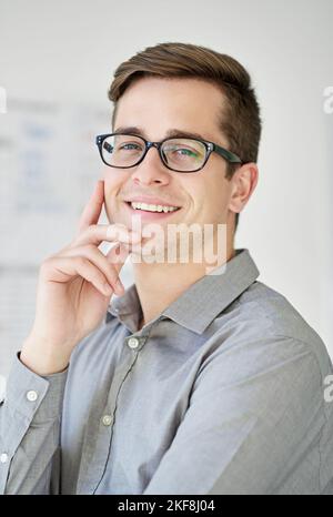 Die Gründung eines Unternehmens ist nicht einfach, aber es lohnt sich. Ein lächelnder junger Geschäftsmann in seinem Büro. Stockfoto