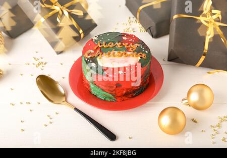 Teller mit leckerer Bento-Torte, Geschenken und Weihnachtskugeln auf weißem Holzhintergrund Stockfoto