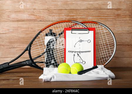 Clipboard mit gezeichneter Schema von Tennisspielen, Schlägern, Bällen, Rock und Flasche auf Holzhintergrund Stockfoto