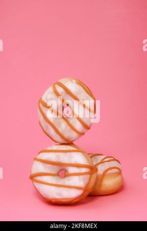 Mini-Donuts mit weißer Glasur auf rosa Hintergrund Stockfoto