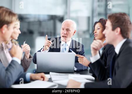 Über den nächsten Schritt des Unternehmens sprechen. Führungskräfte von Unternehmen, die während eines Meetings an einem Tisch sitzen und einen Laptop verwenden. Stockfoto