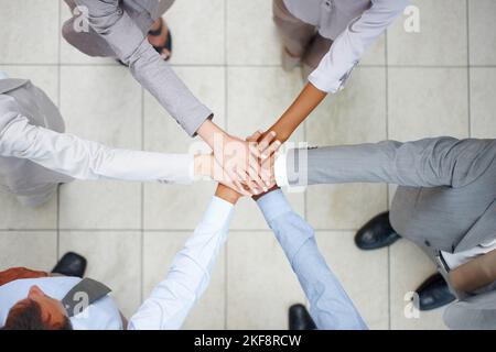 Geschäftsabschlüsse als Einheit – Geschäftsteams. Draufsicht auf sechs verschiedene Kollegen, die ihre Hände in einer Gewerkschaft zusammenlegen. Stockfoto