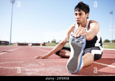 Dehnung vor einem Rennen. Ein junger Läufer streckt seine Beinmuskeln. Stockfoto