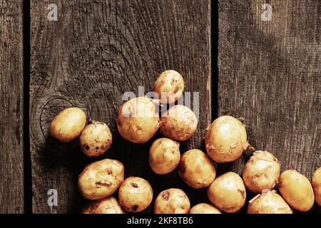 Junge rothaarige, geschälte Kartoffeln liegen aus der Nähe auf einem Holztisch Stockfoto