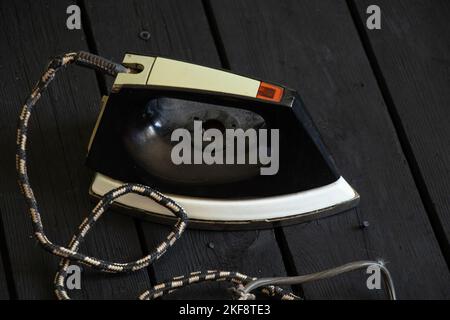 Ein altes elektrisches Eisen steht auf einem schwarzen Holzboden, ein sowjetisches Eisen Stockfoto