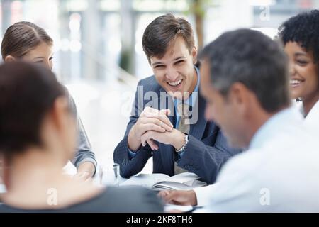 Das Unternehmen erfolgreich machen. Eine vielfältige Gruppe von Geschäftsleuten lacht während eines Meetings. Stockfoto