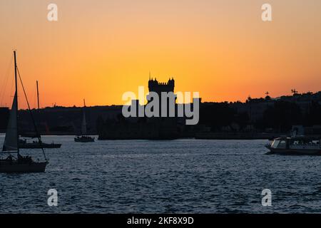 Sonnenuntergang über dem Fluss Tejo in Belém, Lissabon, Portugal. Die Silhouette des Belém-Turms, Torre de Belém. Festung aus dem 16.. Jahrhundert, UNESCO-Weltkulturerbe. Stockfoto