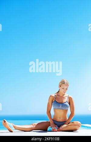 Konzentriere dich auf ihre innere Kraft. Eine junge Frau, die auf einer Terrasse unter blauem Himmel arbeitet. Stockfoto