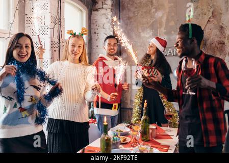 Eine Gruppe von Freunden, die bei der Weihnachtsfeier mit Getränken anstoßen. Stockfoto