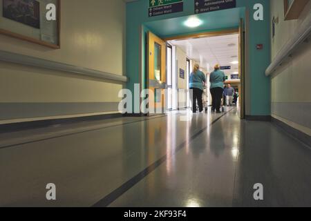 Zwei medizinische Reinigungskräfte gehen mit Geräten durch einen Krankenhauskorridor Stockfoto