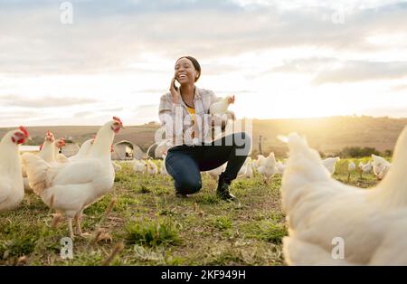 Schwarze Frau, Telefonanruf und Land auf Hühnerfarm mit einem Lächeln für lebende Vorräte im Freien. Glückliche afroamerikanische Bäuerin lächelt an Stockfoto