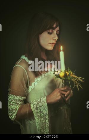 Dunkle Frau mit einer Kerze. Schwarzer Hintergrund Stockfoto