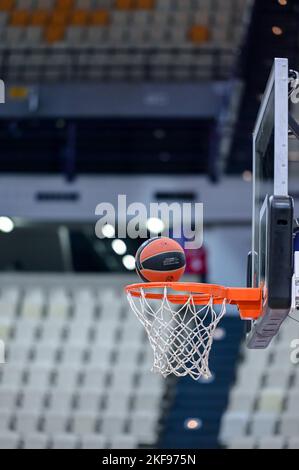 Basketball, der in einem Basketballfeld mit leeren Sitzen ins Netz geht Stockfoto