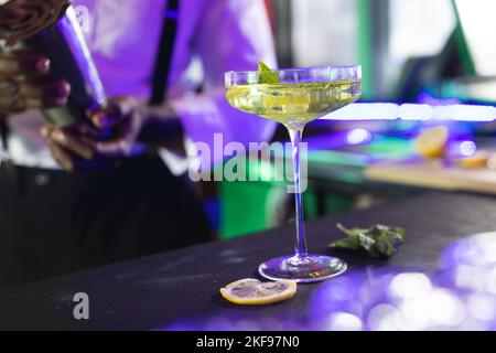 Der mittlere Teil des afroamerikanischen Barkeepers bereitet einen grünen Cocktail an einer Bar zu, selektiver Fokus Stockfoto