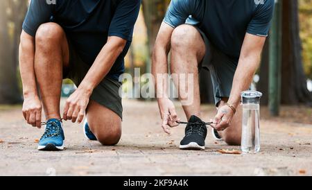 Fitness, Laufen und Männer, die ihre Schuhe binden, während sie ein Cardio-Training im Freien in der Stadt machen. Sport, Schuhe und männliche Athleten laufen für Stockfoto