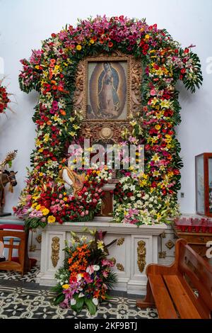 Blumen und Gemälde der Jungfrau Maria in der Kirche von San Antonino Obisbo in San Antonino Castillo Velasco, Oaxaca, Mexiko, erbaut im 16. Jahrhundert. Stockfoto