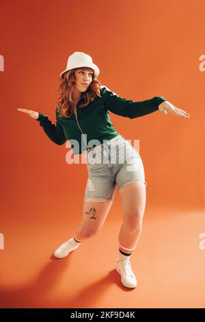 Lebhafte junge Frau, die einige Tanzbewegungen in einem Studio macht. Junge Frau, die eine gute Zeit in legerer Kleidung hat. Stockfoto