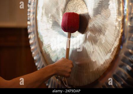 Mann, Der Während Der Spirituellen Praxis Aufgehängte Gong-Übungen Spielt Stockfoto