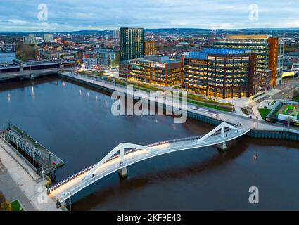 Luftaufnahme von der Drohne in der Abenddämmerung der Squiggly Bridge und des Barclays Campus in Tradeston am River Clyde, Glasgow, Schottland, Großbritannien Stockfoto