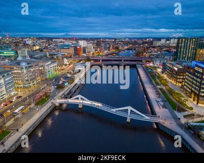 Luftaufnahme von der Drohne in der Dämmerung der Skyline von Glasgow und der Squiggly Bridge über den Fluss Clyde, Schottland, Großbritannien Stockfoto