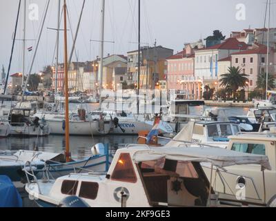 Besuchen Sie Kroatien: Ein abendlicher Spaziergang entlang der Küste in der hübschen Stadt Mali Losinj, mit Booten und Yachten im natürlichen Hafen. Stockfoto