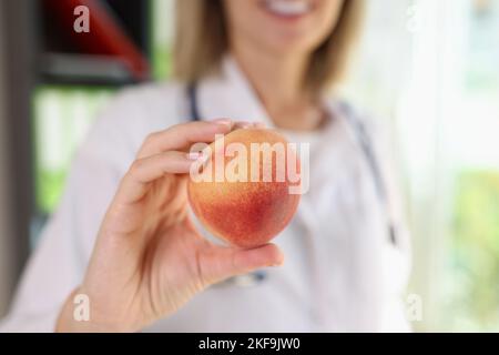 Ärztin hält Pfirsichfrüchte in der Hand, Nahaufnahme. Stockfoto