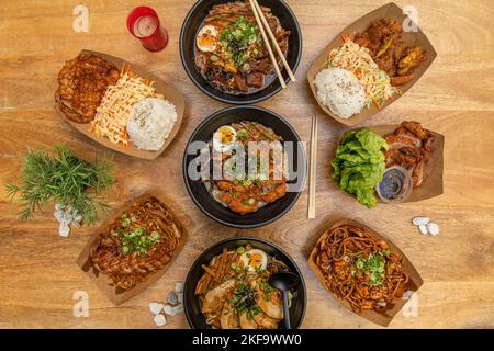 Set von asiatischen Rezepten in schwarzen Schüsseln und Street Food Containern, verschiedene Ramens mit Fleisch, Misosuppe und Nudeln, Hühnercryo und gebratene Ente Stockfoto