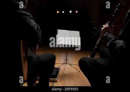 Zwei Musiker, die vor einem Notenblatt sitzen, um Gitarre und Klarinette zu spielen Stockfoto