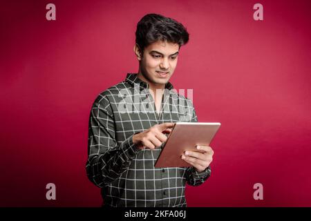 Online-Zahlung Im Internet. Ein junger Mann, der eine sichere Online-Zahlung über eine Banking-App auf seinem Smartphone tätigt, konzentriert und in den Prozess involviert Stockfoto