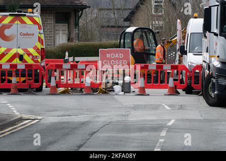 Die Straße wurde gesperrt, während Männer am Bagger arbeiten, der die Straße grub. Straßenarbeiten. Stockfoto