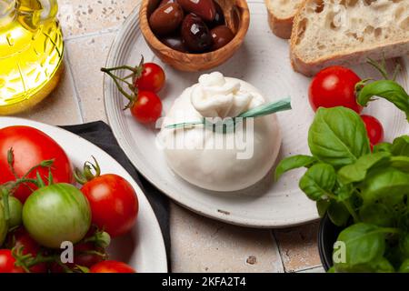 Burrata-Käse, verschiedene Tomaten und Oliven. Italienische Küche Stockfoto