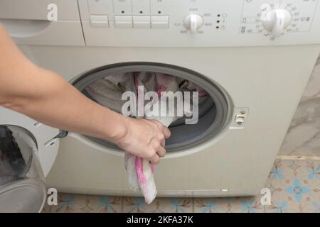 Mann nimmt Kleidung aus der Waschmaschine. Hand nimmt gewaschene Kleidung heraus. Hochwertige Fotos Stockfoto