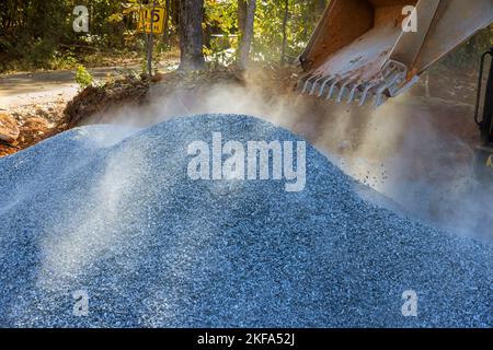 Während der Reparaturarbeiten auf der Baustelle wurde der Bobcat-Lader-Bagger zum Entladen von Schotter verwendet Stockfoto