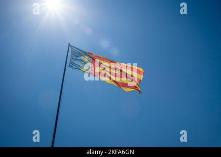 Valencianische Gemeinschaftsflagge gegen eine blaue Flagge. Stockfoto